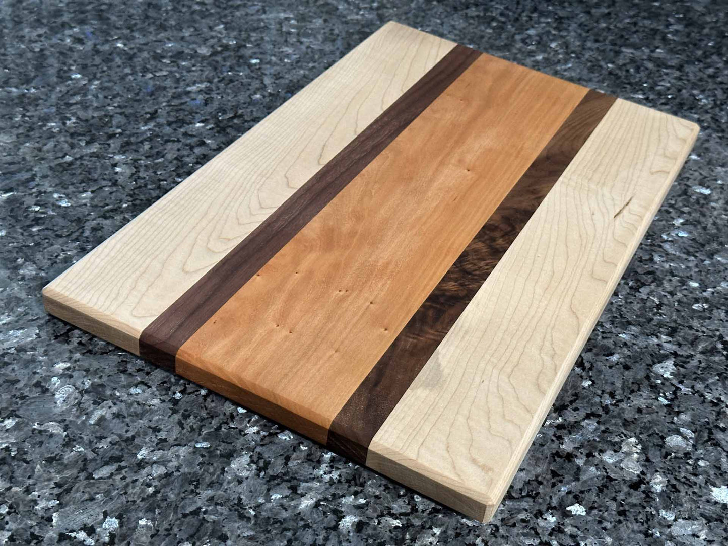 A combination of maple and cherry hardwoods with striking black walnut accents, this long grain cutting board blends function with style.