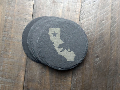 These California themed slate coasters are a real "bear" necessity to show off some state pride. Laser engraved with either the state's outline, lone star, and a grizzly bear or the California flag, they’re a bold way to keep your drinks in check. Made from durable slate, these coasters are both functional and stylish, making them a perfect addition to any home or as a gift for lovers of the Golden State.