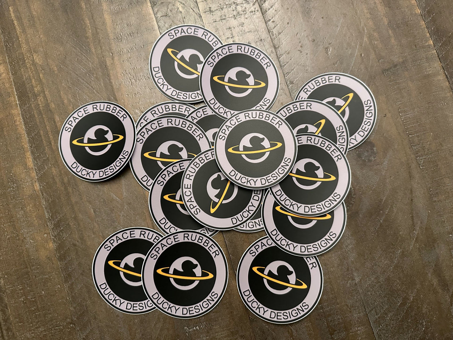 Space Rubber Ducky Designs decal sticker. 3" circle die cut vinyl decal. Matte finish and weather resistant. Features the company logo. 